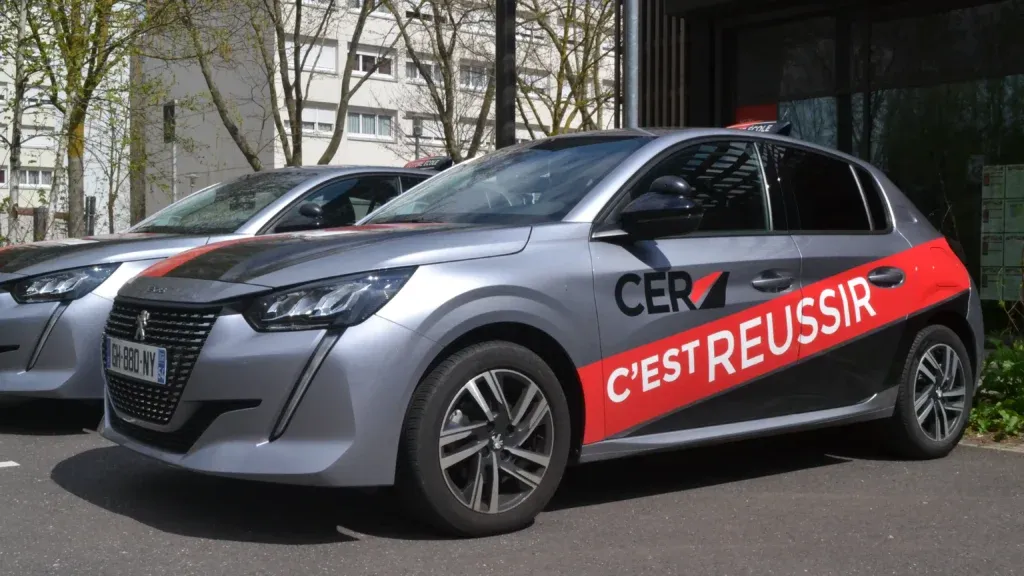 Voitures d’auto-école du réseau CER, portant la devise « CER c’est réussir » sur leur habillage gris et rouge