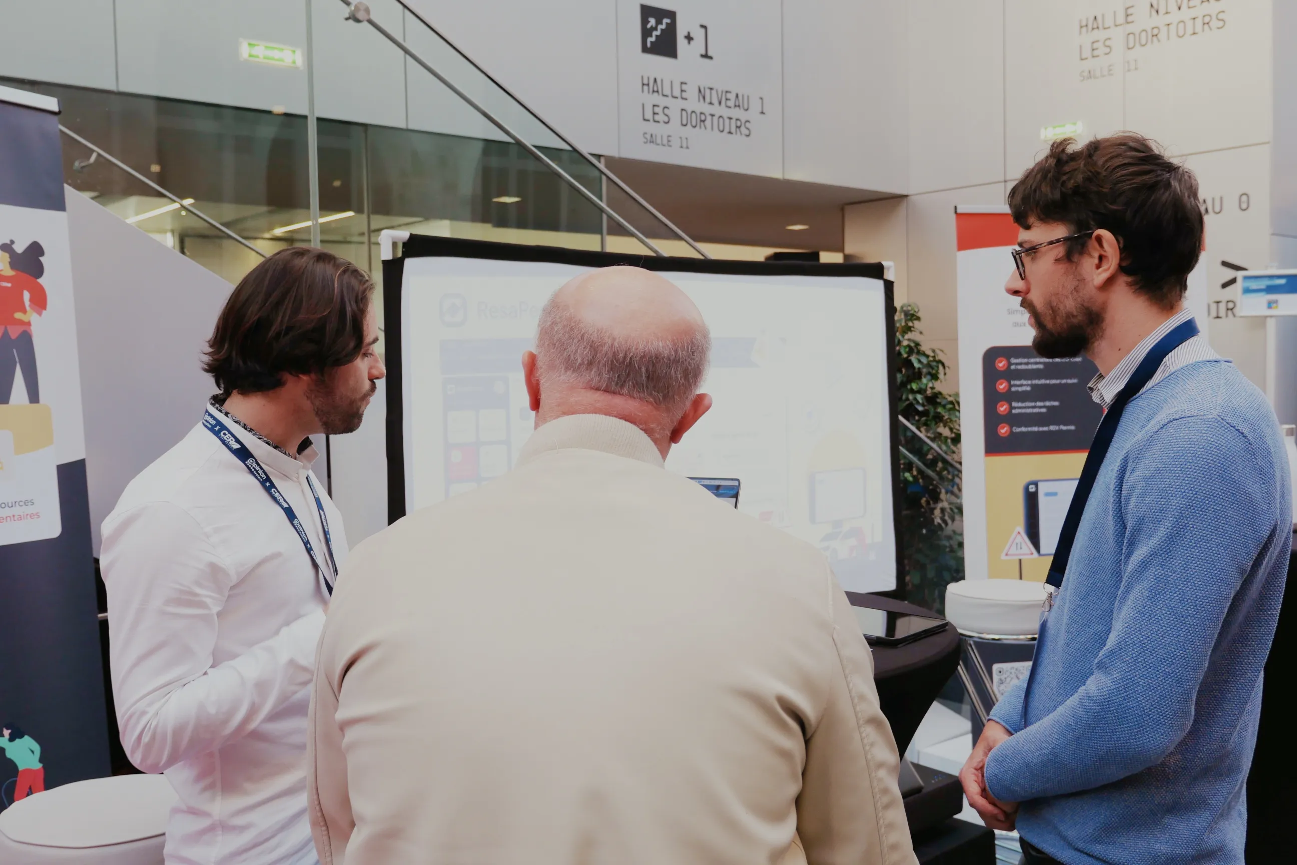 Deux membres de l'équipe ResaPermis présentent l'outil à un responsable d'auto-école sur leur stand, au congrès du réseau CER.